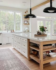 a large kitchen with an island in the middle and two lights hanging from the ceiling