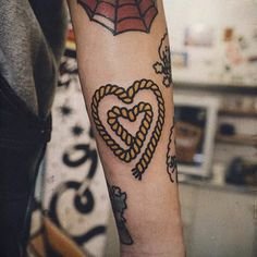 a person with a spiderman tattoo on their arm holding a heart shaped knot in the shape of a heart