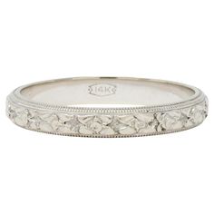 an antique style wedding band with flowers and leaves on the side, in white gold