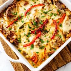 a casserole dish with meat, cheese and peppers in it on a cutting board