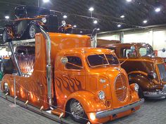 an orange semi truck with flames painted on it's side at a car show