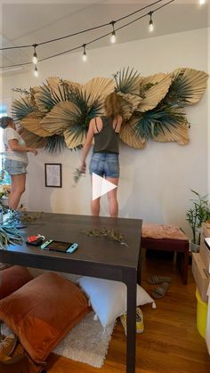 two women are standing in front of a large piece of art that is hanging on the wall