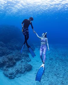 two people are diving in the ocean with their snorkels and holding hands