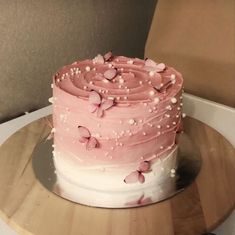 a pink and white cake sitting on top of a wooden plate