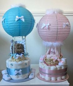 two diaper cakes sitting on top of a table next to each other with teddy bears in them