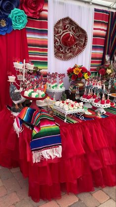 a mexican themed dessert table with red tulle skirt and colorful decorations on the wall