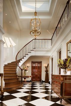 a foyer with black and white checkered flooring, chandelier and stairs