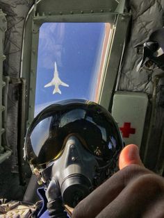 a person wearing a helmet and goggles is looking at an airplane through the window