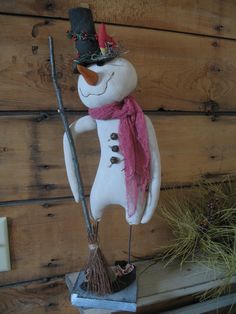 a snowman with a hat and scarf holding a broom on top of a shelf