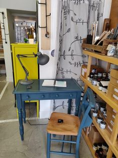 a blue desk and chair in a room filled with shelves full of crafting supplies