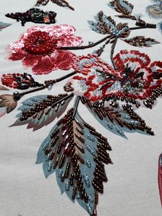 an embroidered fabric with flowers and leaves on it