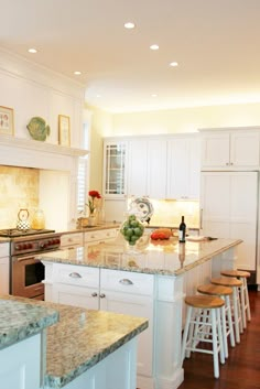 a large kitchen with white cabinets and marble counter tops, along with an island in the middle