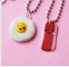 two necklaces with food on them sitting next to each other in front of a pink background