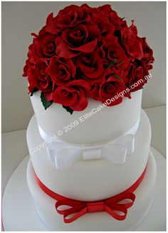 a three tiered cake with red roses on top