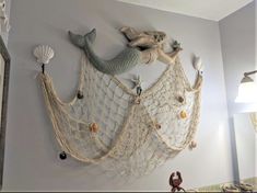 there is a fish net hanging on the wall with shells and other things around it