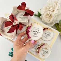 a hand holding a ring in front of two small boxes with flowers on them and the words sparkle written on it