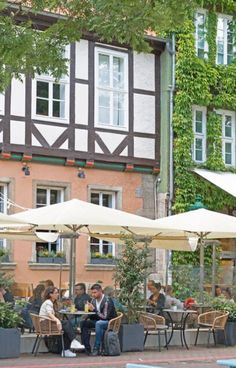 people are sitting at tables under umbrellas outside