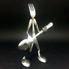 a fork and knife sculpture made out of silverware on a black surface with light coming from behind it