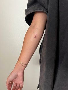 a woman's arm with a tiny tattoo on the left side of her arm