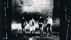 three men standing in front of a brick wall