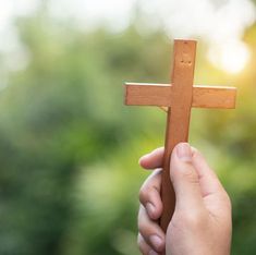 a person holding a wooden cross in their hand