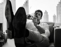 a man sitting in a chair with his feet propped up on the table while brushing his teeth