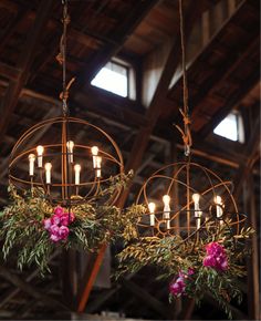 two chandeliers hanging from the ceiling with flowers and greenery on each one