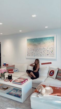 a woman sitting on top of a white couch in a living room