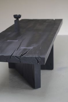 a table made out of black wood with an iron handle on the top and bottom