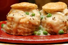 two biscuits covered in cheese and peas on a red plate