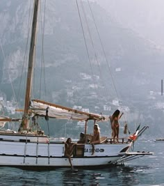 three people on a sailboat in the water