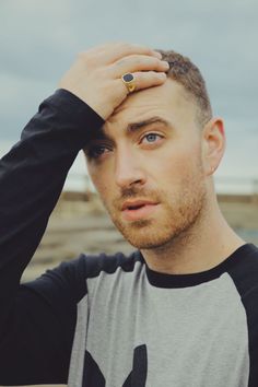 a man with a ring on his left hand is looking at the camera while wearing a black and gray shirt