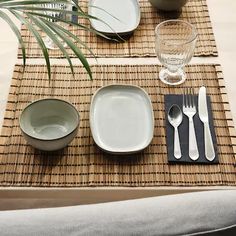 the place setting is ready to be served with silverware and glassware, as well as a palm leaf