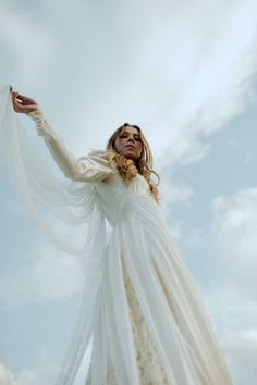 a woman in a white dress is flying through the air with her arms spread out