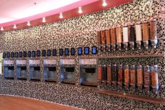 a row of soda machines sitting next to each other on a wall covered in black and white tiles