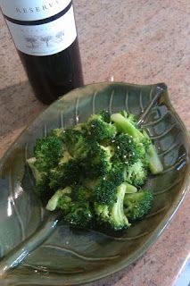 broccoli on a green plate next to a bottle of wine