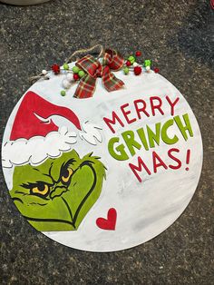 a merry grinch mas sign on the ground with santa's helper hat