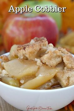 a white bowl filled with apples and crumbs on top of a wooden table