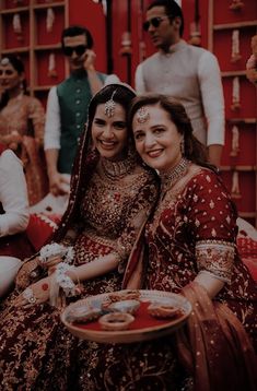 two brides are sharing a laugh as they sit on the floor in front of their guests