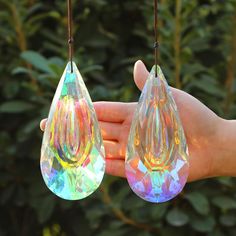 two clear glass tears hanging from a string in front of some bushes and trees