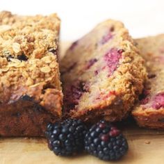 some fruit and bread are on a cutting board next to blackberries, raspberries and oatmeal