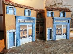 two small buildings made out of cardboard sitting on top of a table