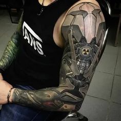 a man with tattoos on his arm sitting down