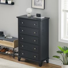 a black chest of drawers next to a window