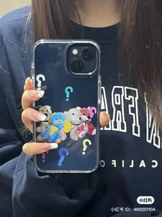 a girl holding up her phone case with some stickers on it's back