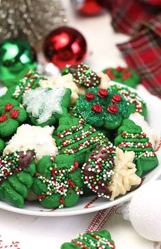 a white plate topped with cookies covered in green and red icing next to christmas decorations