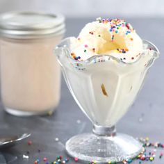 a dessert in a glass with sprinkles on the table next to it