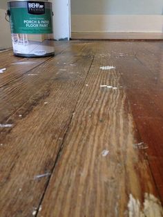 a can of paint sitting on top of a wooden floor next to a white door