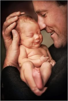 a man holding a newborn baby in his arms and touching it's head with the other hand