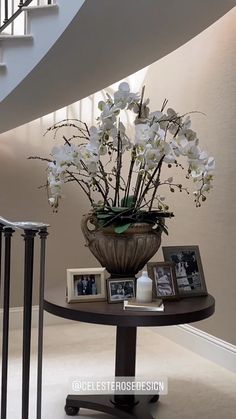 there is a vase with white flowers on the table in front of the staircases